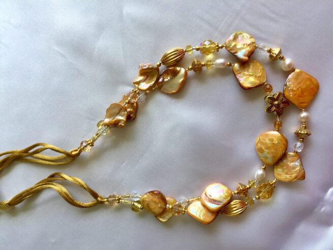 collana color giallo oro madreperla due fili di nome Luminosa Oro perle cristalli distesa sfondo seta bianca