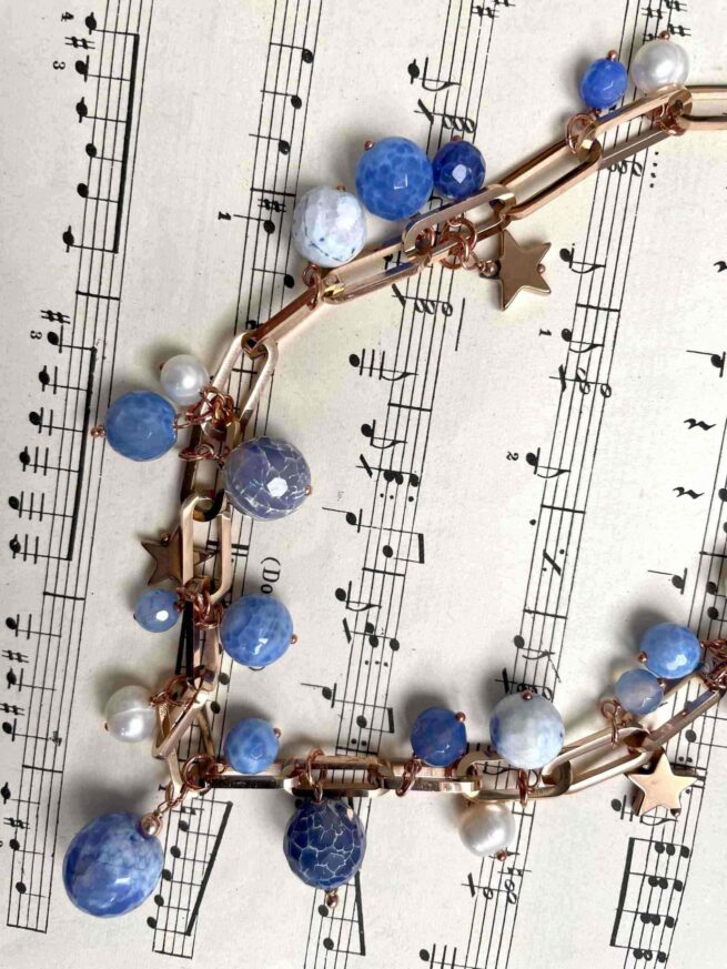collana azzurra agata perle acciaio nome Fiordaliso distesa su spartito musicale